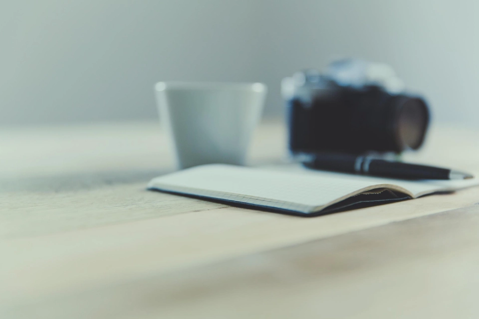 Tasse, Fotoapparat, Heft und Stift